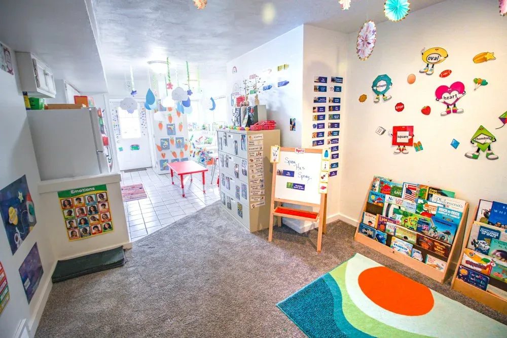 Classroom with bookshelves, activity boards, and a play rug