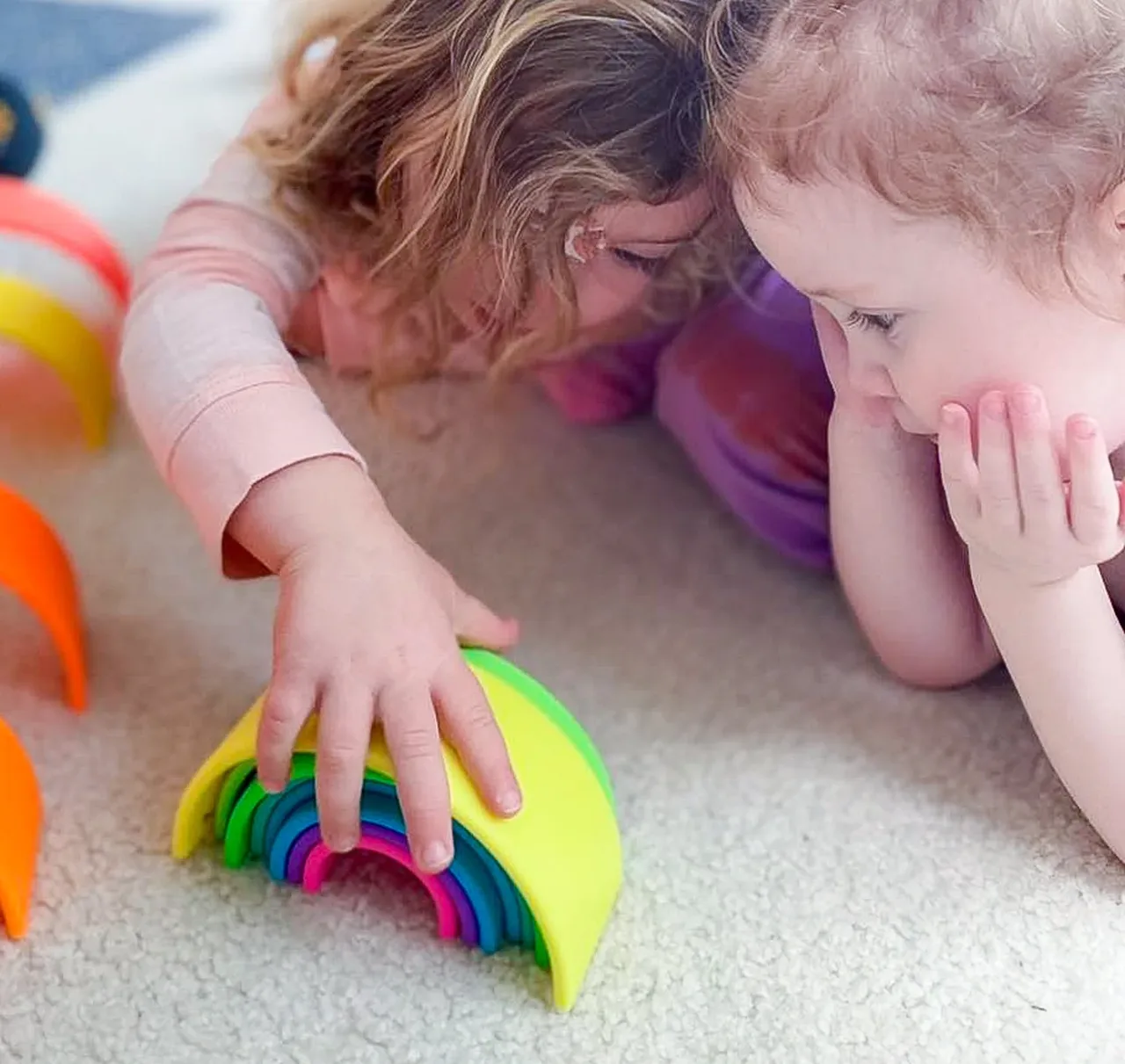 Children exploring colorful nested rings on the floor