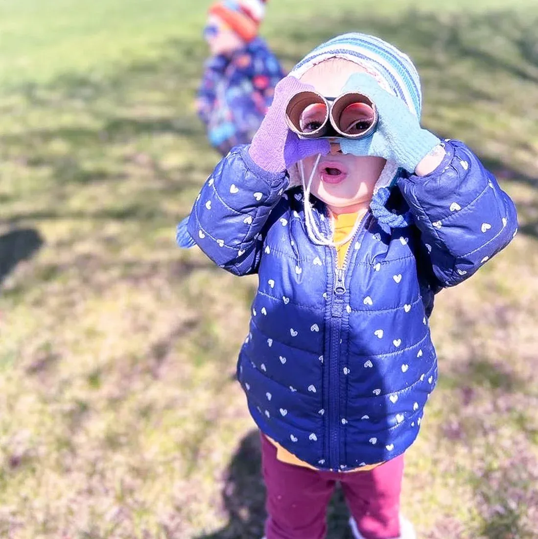 Child looking through toy binoculars outdoors