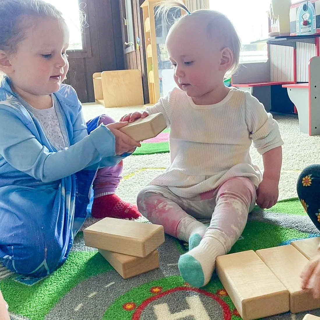 An older child helping a younger child during block play