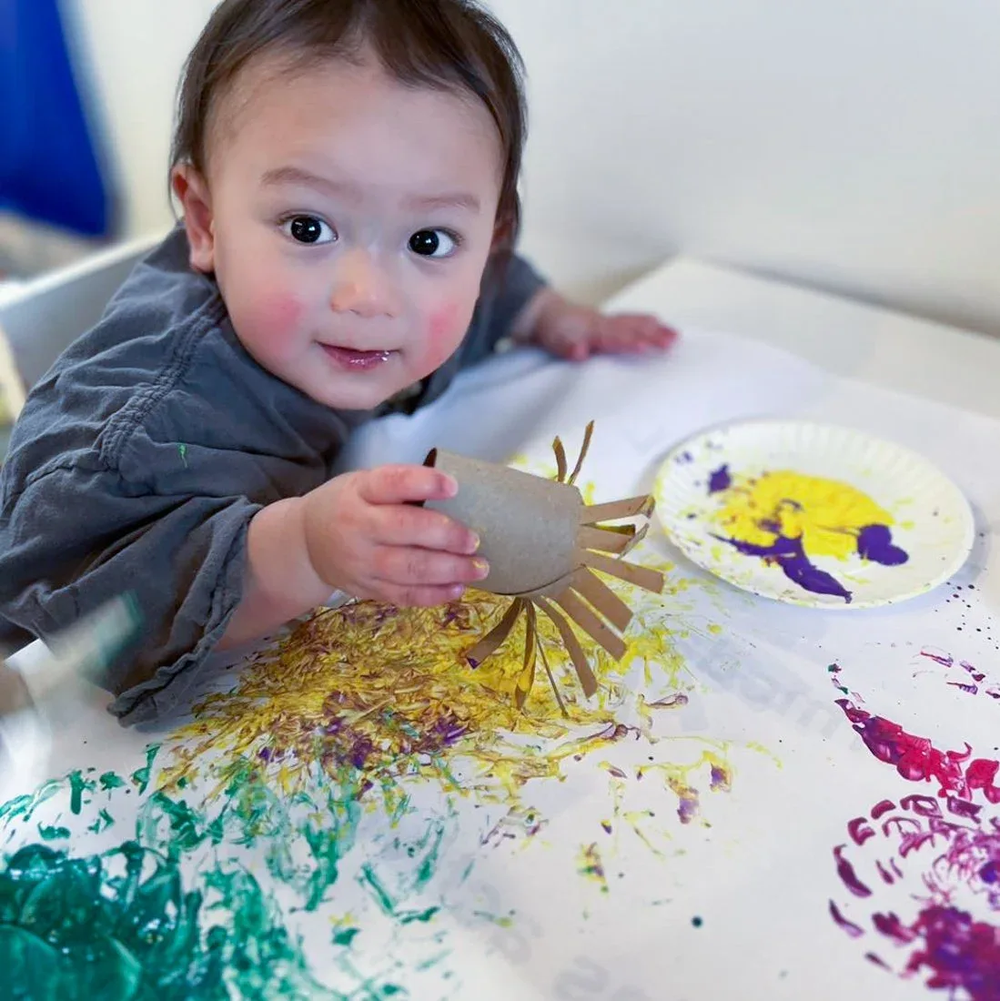 A child painting with yellow paint at an activity table