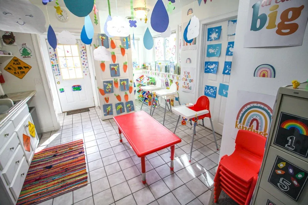 Red table and chairs beneath hanging decorations and children's artwork