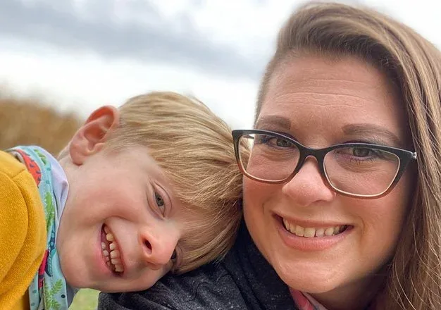 Miss Ashley smiling in a selfie with a child outdoors