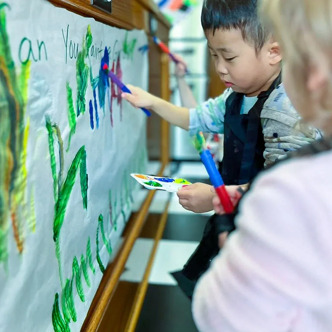 A child painting at a wall-mounted easel