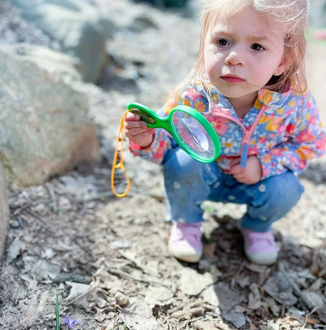 Child exploring outdoors with a magnifying glass