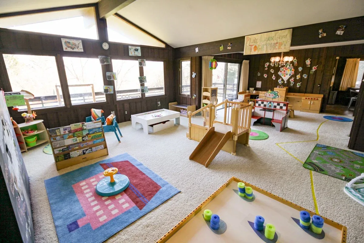 Applewood playroom with floor rugs, low shelves, and a small slide at BBDS Applewood Drive, Madison, WI