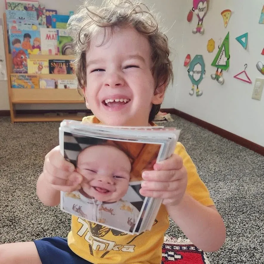 Smiling child holding a photograph during a classroom activity